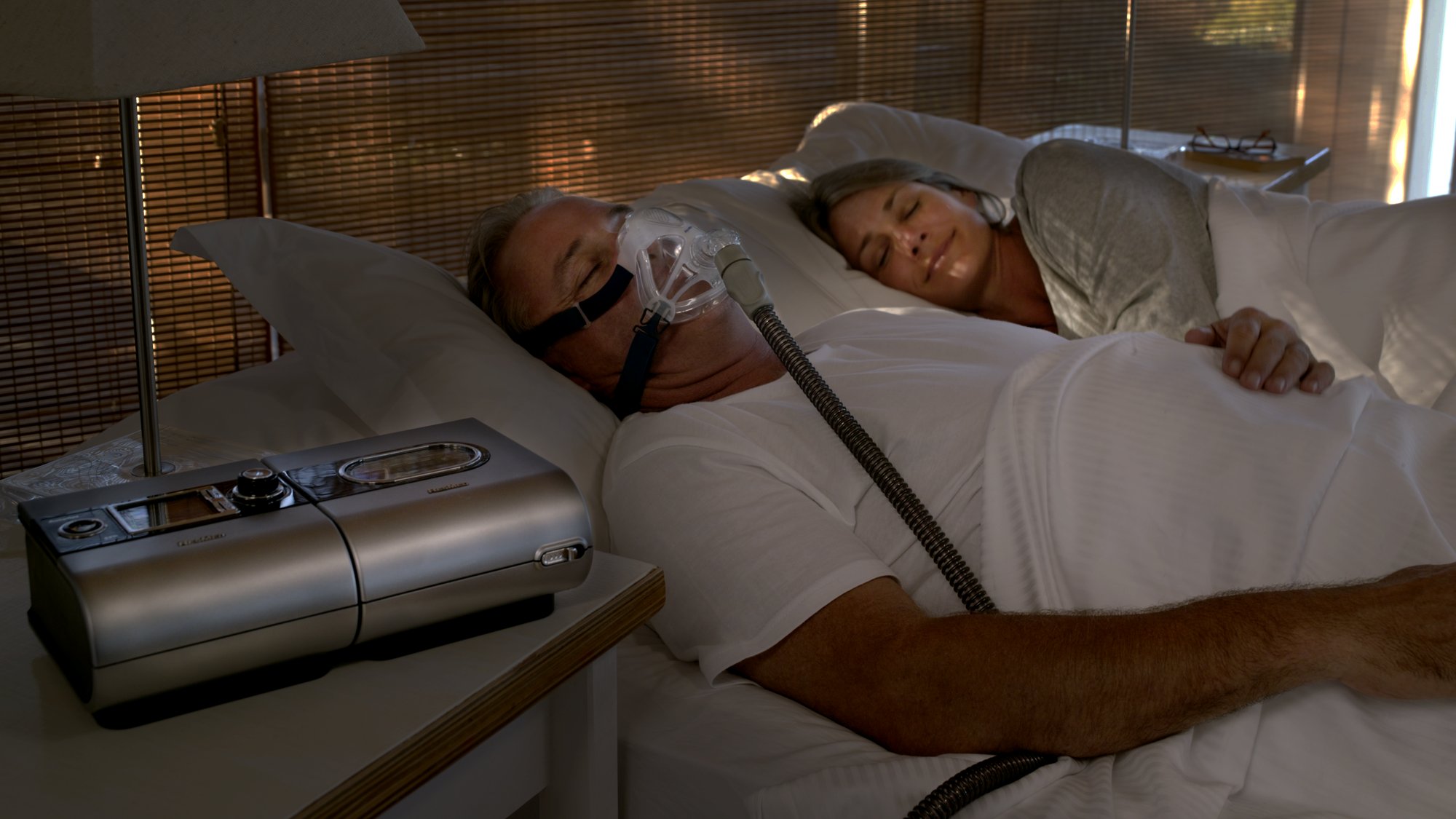 Person lying in bed using a CPAP machine with a nasal mask