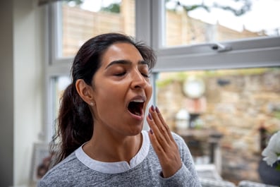 Person experiencing daytime fatigue and yawning at home.